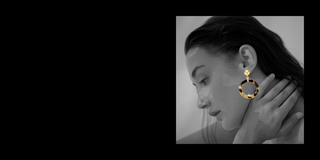 Woman wearing gold hoop earrings with a black border