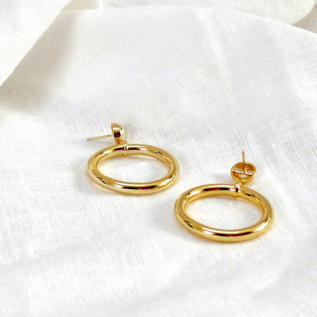 Chunky gold hoop earrings from the Audrey collection by Misia Mae. The chunky gold earrings are on a white linen cloth