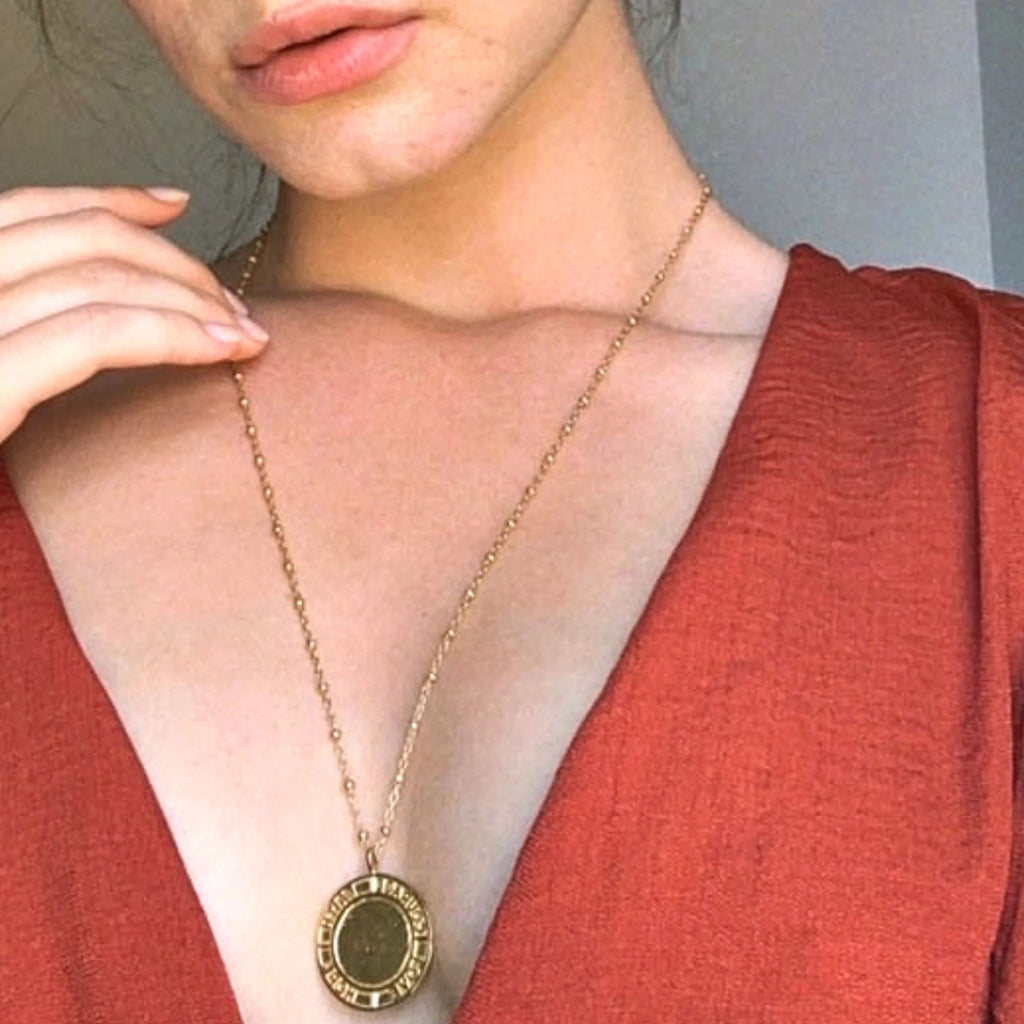 A woman in red dress wearing a gold courage necklace by Misia Mae