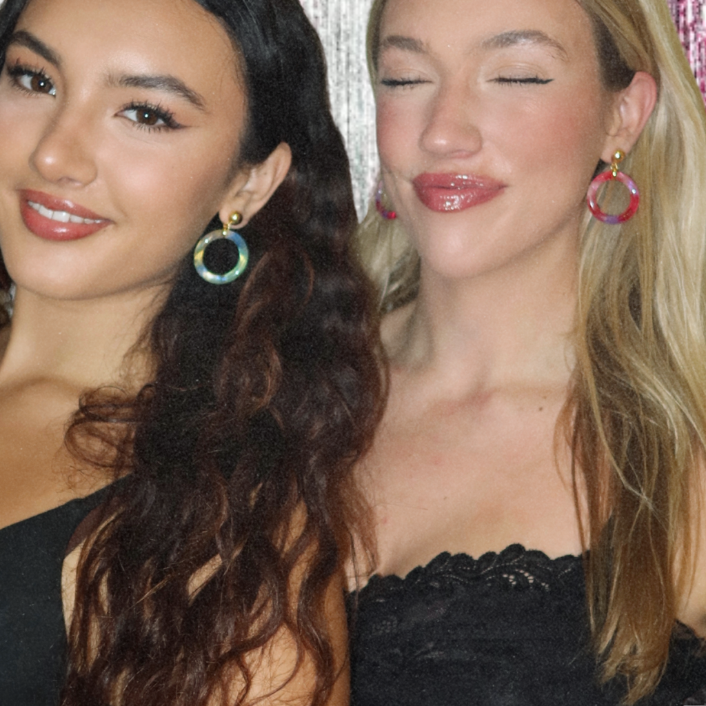 Two women wearing colorful hoop earrings against a neutral background