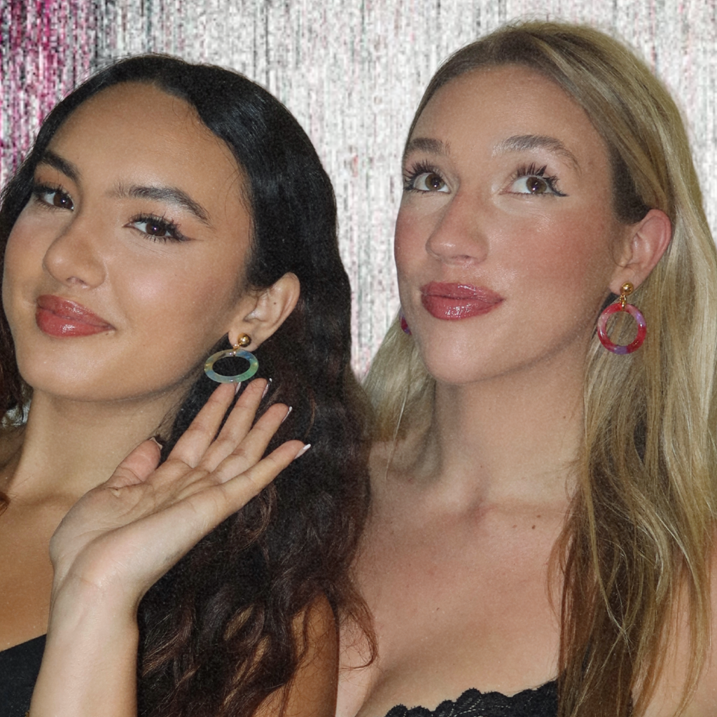 Two women wearing tortoiseshell hoop earrings with a decorative background
