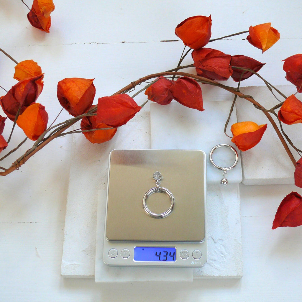 Large silver hoop earrings from Audrey collection by Misia Mae. The earrings are on scales showing weight of 1 earring, 4.34g