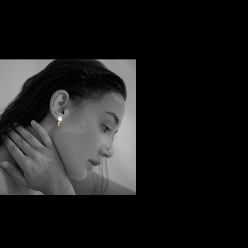 Close-up of a person wearing an earring with a plain background