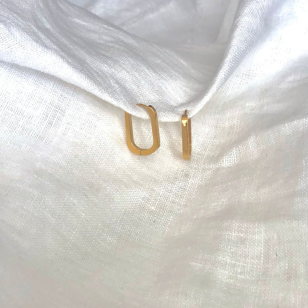 gold rectangle earrings by Misia Mae on a white linen fabric