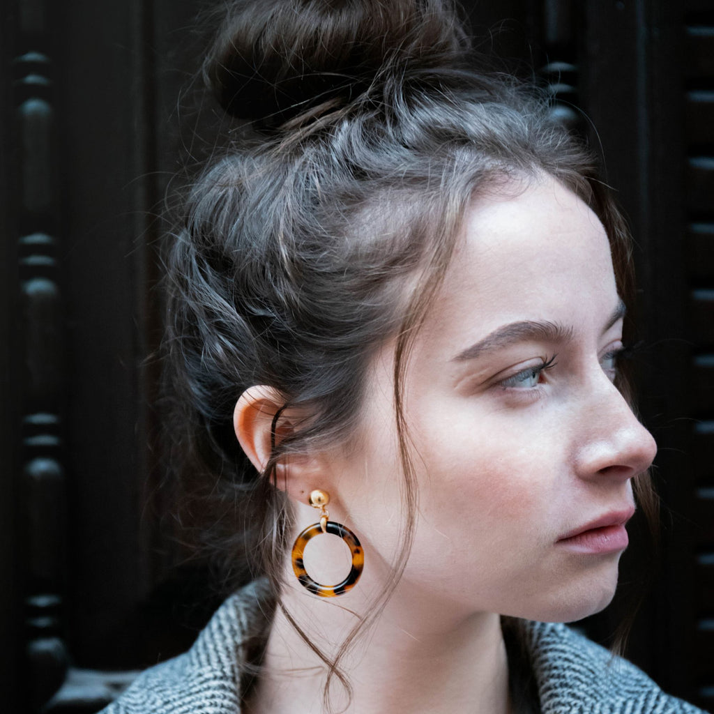 A dark blonde hair model wearing tortoiseshell hoop earrings in brunette from the Audrey collection by Misia Mae