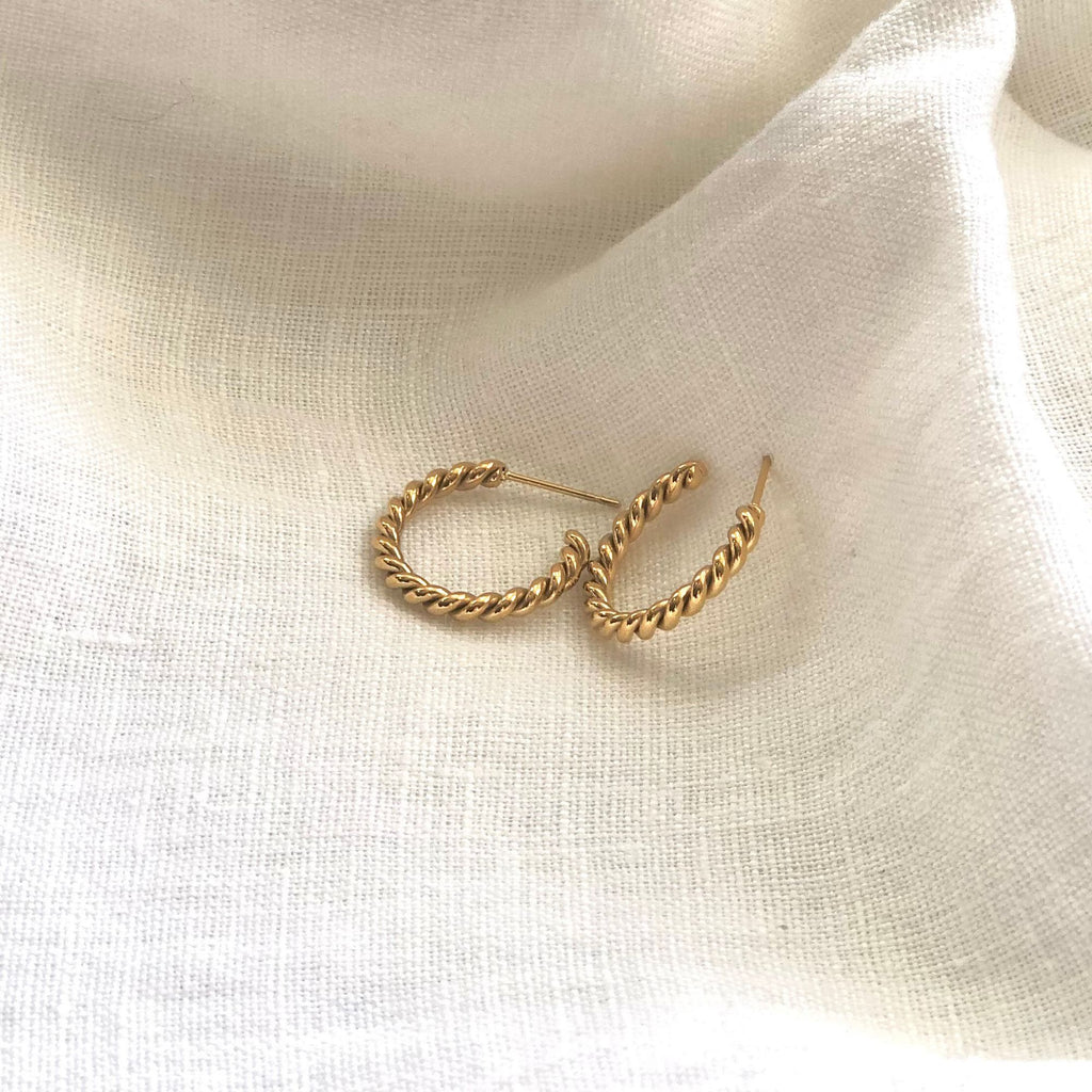 twisted gold earrings from the Iris collection by Misia Mae on a white linen cloth