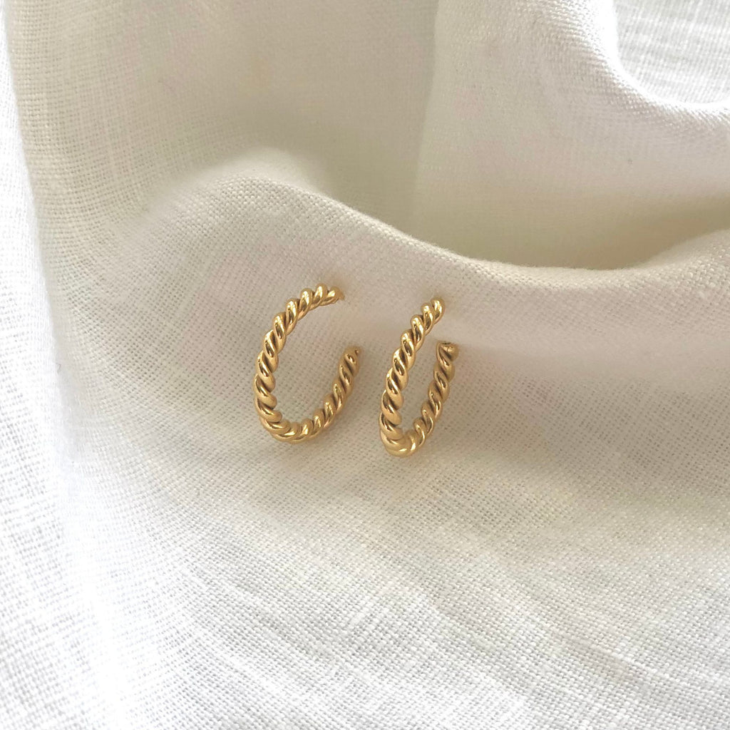 twisted gold earrings from the Iris collection by Misia Mae on a white linen cloth