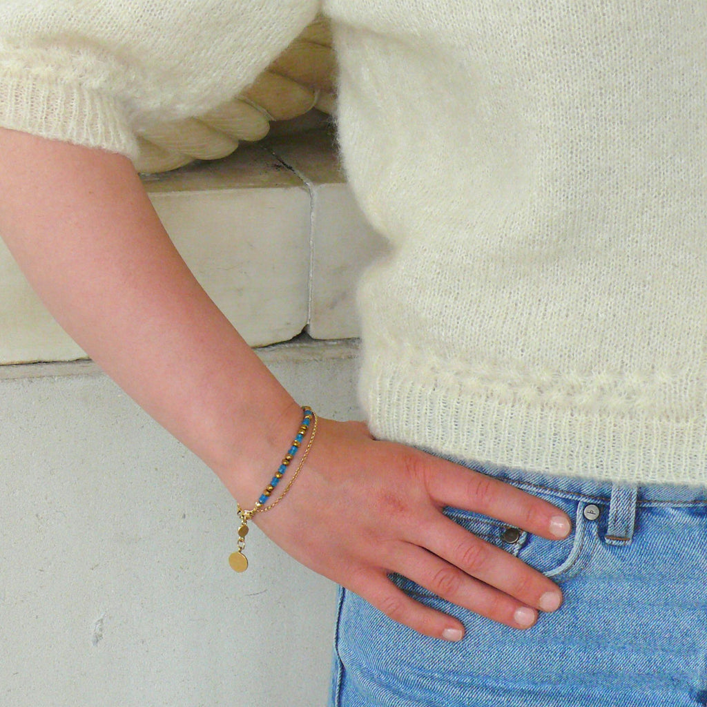 A woman wearing jeans and cream knitted cardigan and an apatite bracelet by Misia Mae